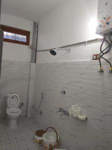 a bathroom with a toilet and a white brick wall at The Bunker House in Chopta +21 photos