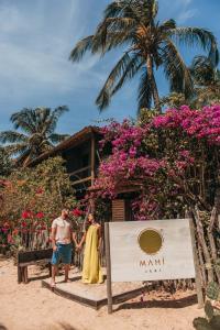 a man and woman standing in front of a sign on the beach at Pousada Mahí in Jericoacoara