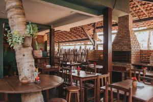 a restaurant with wooden tables and chairs and brick walls at Pousada Mahí in Jericoacoara