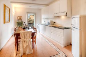 eine Küche mit weißen Schränken und einem Tisch mit Stühlen in der Unterkunft Dama charming apartment 100m from Piazza del Campo in Siena