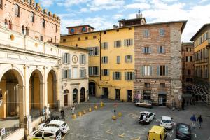 eine Gruppe von Gebäuden mit Autos, die in einer Straße geparkt sind in der Unterkunft Dama charming apartment 100m from Piazza del Campo in Siena