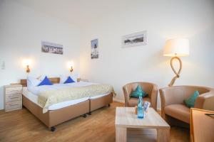 ein Schlafzimmer mit einem Bett, einem Stuhl und einem Tisch in der Unterkunft Hotel Windrose Borkum in Borkum