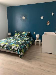 Gîte de Lafayette في Pionsat: غرفة نوم بسرير وجدار ازرق
