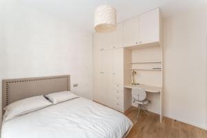 - une chambre blanche avec un lit et un bureau dans l'établissement Luxury home in heart of PARIS!Opera/Eurostar 4pers, à Paris