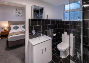 a bathroom with a toilet and a sink and a bed at Royal Lion Hotel in Tenby +106 photos