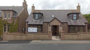 une grande maison en briques avec un panneau en face de celle-ci dans l'établissement Outlander Boutique B&B King, à Cruden Bay