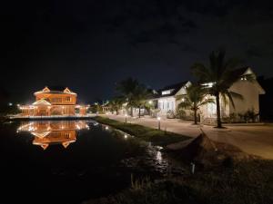 Ban Mae Cho的住宿－MonMin Farmstay，夜晚在池塘里反射的房屋