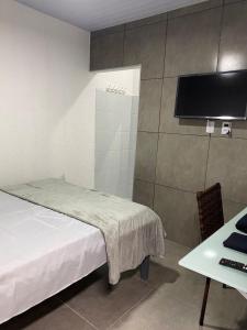 Schlafzimmer mit einem Bett, einem Schreibtisch und einem TV in der Unterkunft GYN SUITES - SUITES EM GOIÂNIA GO in Goiânia