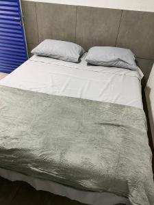 uma cama com lençóis brancos e almofadas em GYN SUITES - SUITES EM GOIÂNIA GO em Goiânia