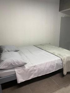 1 cama con sábanas blancas y almohadas en una habitación en GYN SUITES - SUITES EM GOIÂNIA GO, en Goiânia