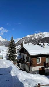 a house is covered in snow in front of a mountain at Appartamento Rin, Livigno in Livigno