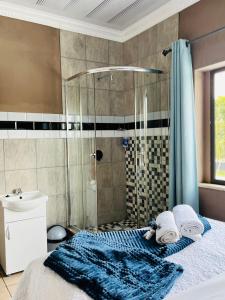 a bathroom with a shower and a bed with towels at Abecor Hotel in Welkom