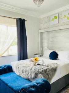 a bedroom with a bed with a blanket and a blue couch at Abecor Hotel in Welkom