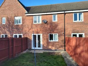 a brick house with a fence in front of it at Ormonde Close 3 bed contractor family home Grantham in Grantham