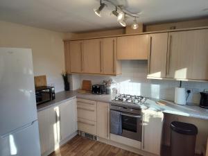 eine Küche mit weißen Geräten und Holzschränken in der Unterkunft Ormonde Close 3 bed contractor family home Grantham in Grantham