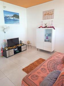 a living room with a bed and a tv at Maison charmante à Petit-Bourg avec piscine partagée in Petit-Bourg