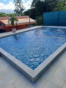 uma grande piscina com água azul em Maison d'une chambre avec piscine partagee terrasse amenagee et wifi a Petit Bourg em Petit-Bourg