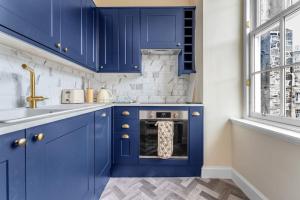cocina con armarios azules y horno en Boutique Modern Royal Mile Apartment Sleeps 4, en Edimburgo