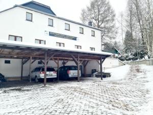 two cars parked in front of a building in the snow at Pizzeria Pension Damiano in Muldenhammer