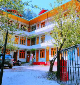 an orange and white building with a tree in front of it at Highland Gojh Kasol in Kasol