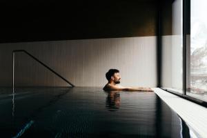 un homme dans une piscine dans un bâtiment dans l'établissement la couronne Hotel & Spa, à Zermatt