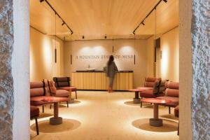 une femme debout dans une salle d'attente avec des chaises dans l'établissement la couronne Hotel & Spa, à Zermatt