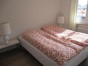 een bed met een rood en wit dekbed in een slaapkamer bij Apartment Casa Selva Hauggaard by Interhome in Valbella