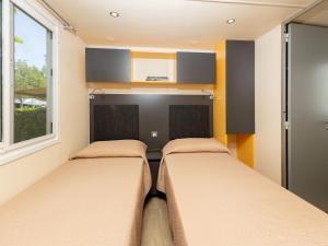 two beds in a small bedroom with a window at Holiday Home San Francesco Camping Village by Interhome in Rivoltella