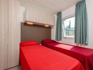 two red beds in a room with a window at Holiday Home Garda Suite Deluxe by Interhome in Rivoltella
