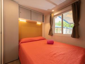 a bedroom with a orange bed and a window at Holiday Home San Francesco Camping Village by Interhome in Rivoltella