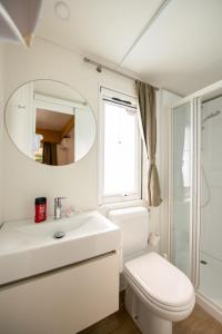 W łazience znajduje się umywalka, toaleta i lustro. w obiekcie Holiday Home San Francesco Camping Village by Interhome w mieście Rivoltella del Garda