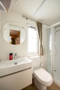 a bathroom with a sink and a toilet and a mirror at Holiday Home San Francesco Camping Village by Interhome in Rivoltella