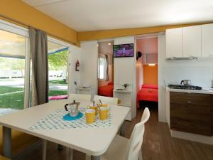 kuchnia i salon z białym stołem i krzesłami w obiekcie Holiday Home San Francesco Camping Village by Interhome w mieście Rivoltella del Garda