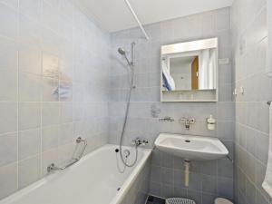 een badkamer met een wastafel, een bad en een spiegel bij Apartment Nr-05 Haus Sursilvana by Interhome in Lenzerheide