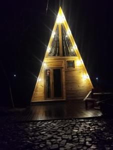 un edificio de madera con techo triangular con luces. en Căbănuța La Gălățanu, en Vulcan