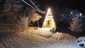 a house in the snow with a light on it at Căbănuța La Gălățanu in Vulcan +4 photos