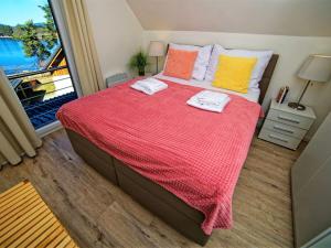 a bedroom with a bed with a red blanket and a window at Holiday Home Lakeside Village 13 - - sauna by Interhome in Frymburk