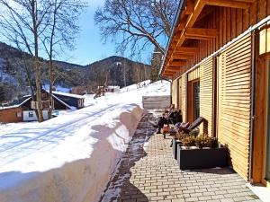 two people sitting on benches outside a building in the snow at Apartment Ski-In Ski-Out Mountain Duplex Portášky3 by Interhome in Pec pod Sněžkou