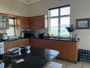 a kitchen with wooden cabinets and a black counter top at Behrs Lair Luxury Villa Simons Town in Cape Town
