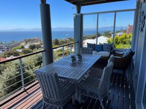 a table and chairs on a deck with a view of the ocean at Behrs Lair Luxury Villa Simons Town in Cape Town