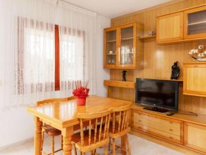 a dining room with a wooden table and a television at Villa Villa Tello by Interhome in L'Ametlla de Mar