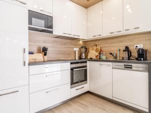 a kitchen with white cabinets and stainless steel appliances at Holiday Home Lakeside Village 22 - - sauna by Interhome in Frymburk