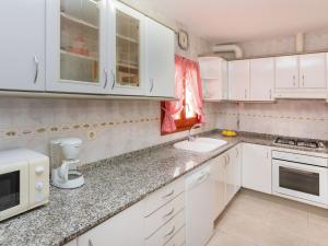 a kitchen with white cabinets and a sink and a microwave at Villa Villa Tello by Interhome in L'Ametlla de Mar
