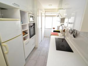 a kitchen with white cabinets and a white refrigerator at Apartment Formentor by Interhome in Salou