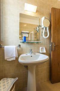 La salle de bains est pourvue d'un lavabo et d'un miroir. dans l'établissement Hotel Genzianella, à Cervia