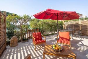 un patio con 2 sillas y una mesa con sombrilla en Appartement entièrement rénové avec Terrasse, en Saint-Tropez