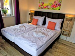 a bedroom with a large bed with orange pillows at Holiday Home Lakeside Village 36 - - sauna by Interhome in Frymburk
