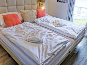 a bed with white sheets and orange pillows at Holiday Home Lakeside Village 36 - - sauna by Interhome in Frymburk