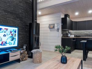 a living room with a fireplace and a kitchen at Holiday Home Westlevi b by Interhome in Sirkka