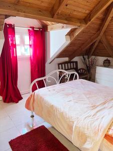 um quarto com uma cama branca e cortinas vermelhas em Villa La Roserie em Ducos